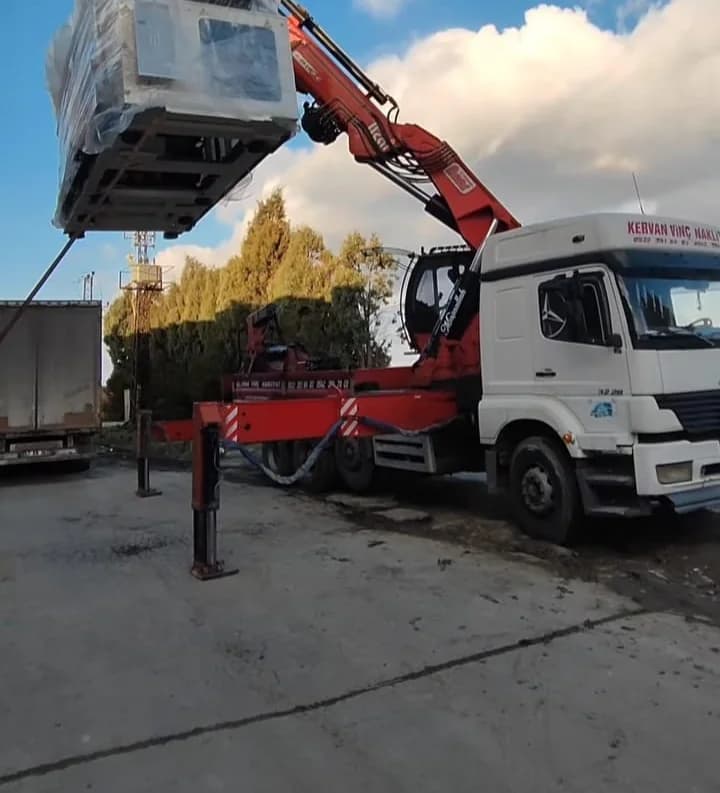Kamyon üstü eklemli yük vinciyle kaldırılan ambalajlı endüstriyel yük