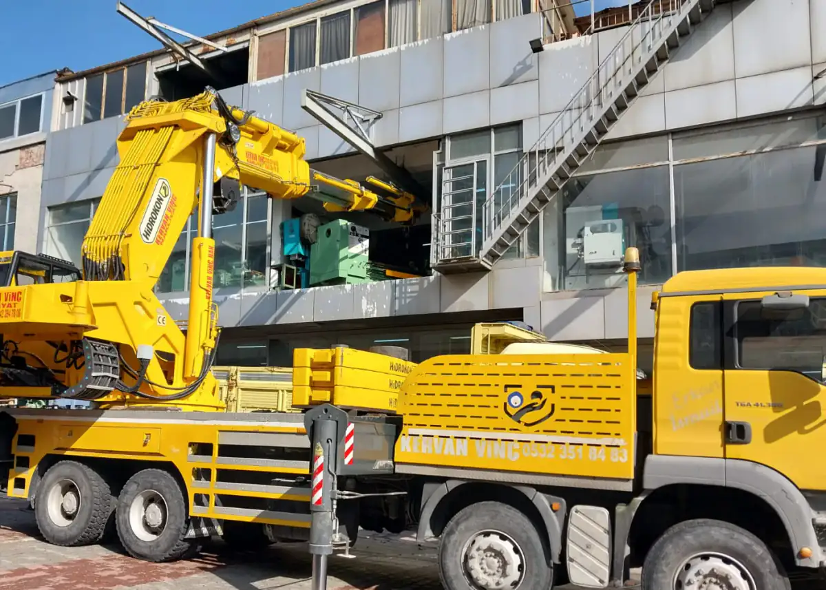 Sanayi sahasında bina önünde konumlandırılmış mobil vinç