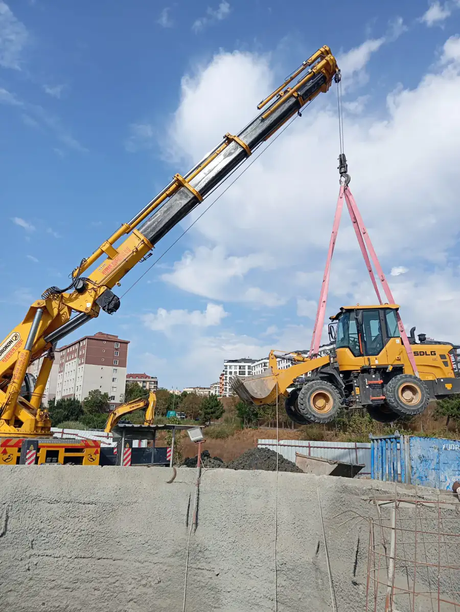 Şantiye alanında iş makinesini kaldıran mobil vinç